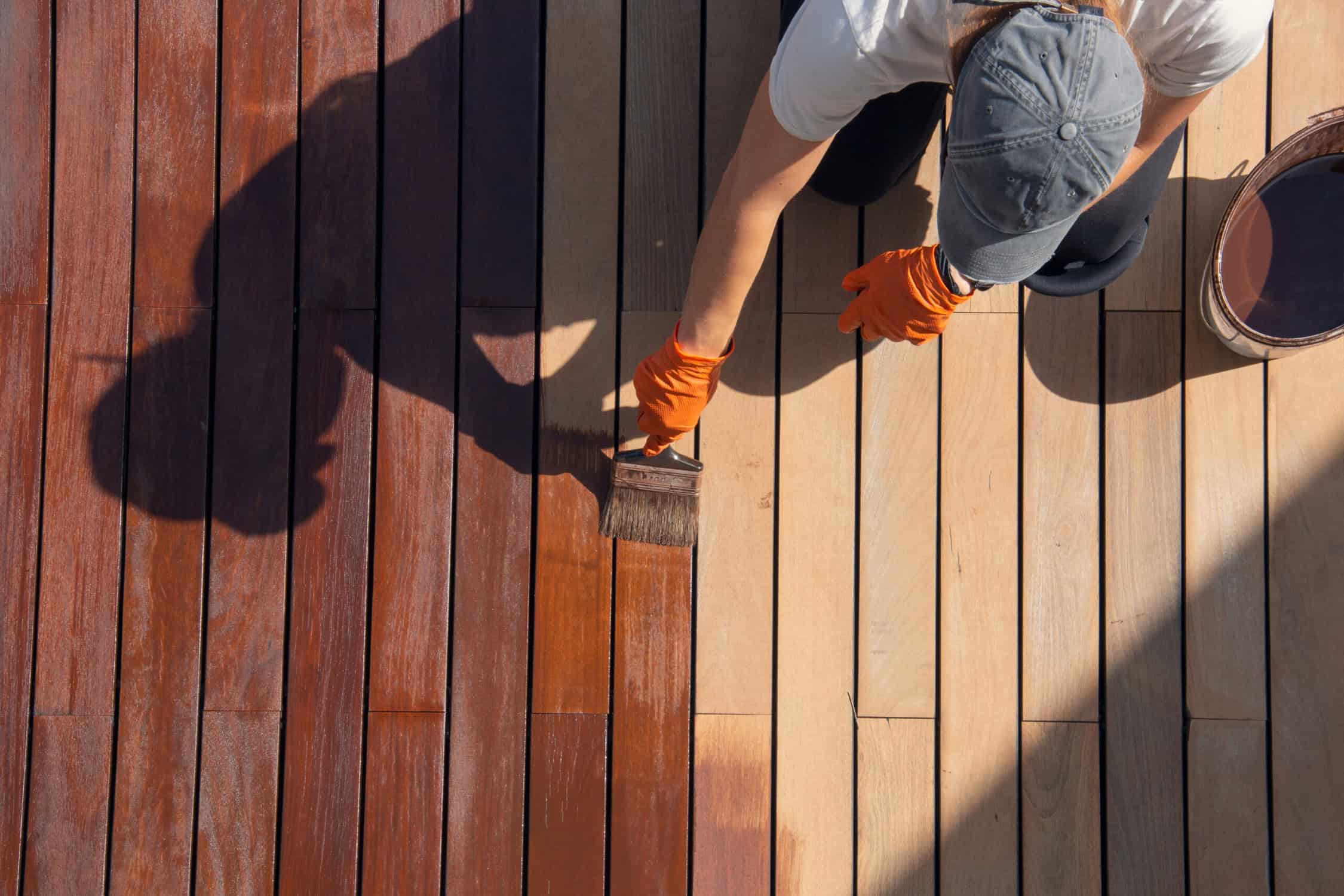 Exterior wood deck sealing and staining, overhead worker applying protective deck stain color Exterior wood deck sealing and staining, overhead worker applying protective deck stain color