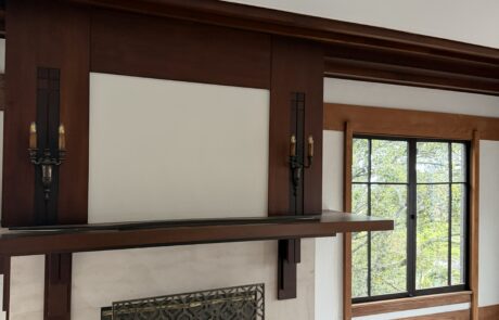 Custom Wood Staining for Fireplace Mantels and Interior Trim A fireplace with a dark stained wood mantel and surround, next to a window with light wood trim.