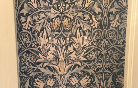 Intricate Patterned Wallpaper Installation Around Light Switches Close up of a beautifully installed blue and gold floral wallpaper with precise cuts around light switches.