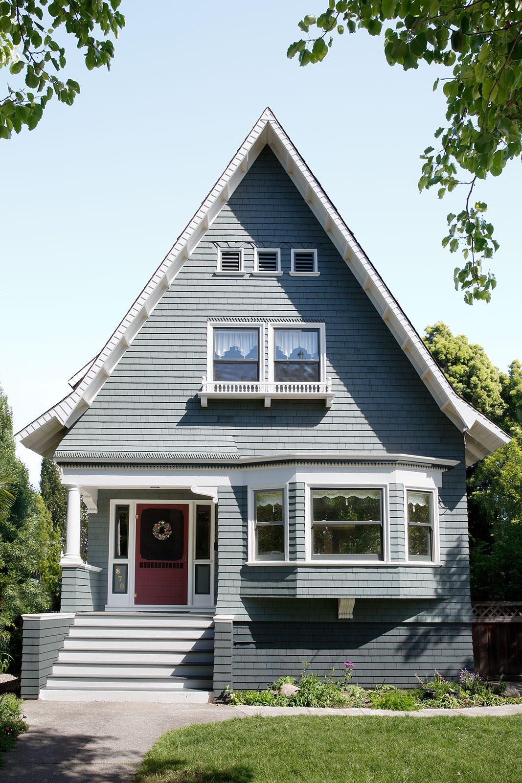 Residential Exterior Painting for Enhanced Curb Appeal Front view of a charming home with teal shingle siding, white trim, and a vibrant red front door.