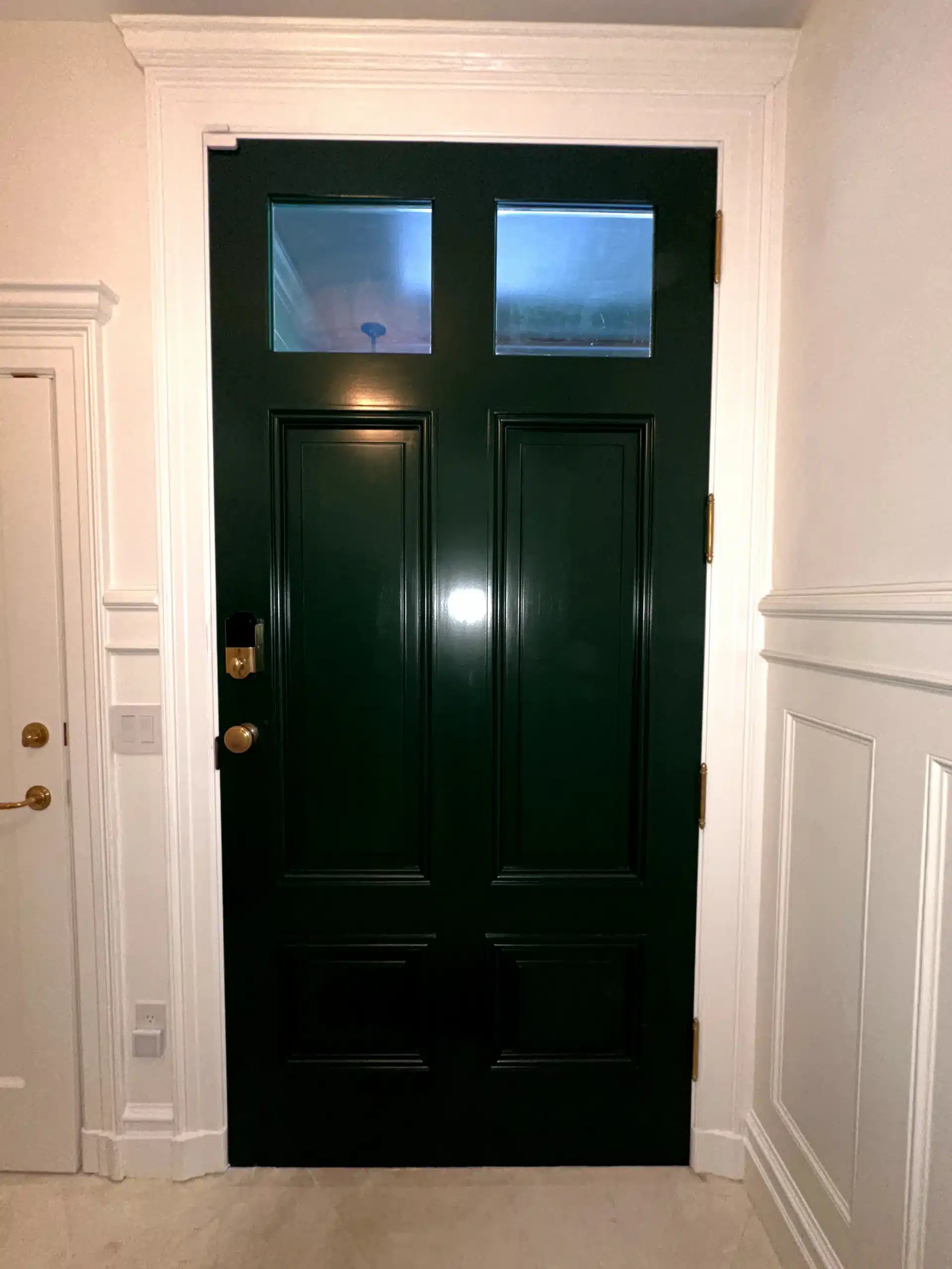 Elegant Dark Green Front Door Painting with White Trim A freshly painted dark green front door with a glossy finish, surrounded by crisp white interior trim.