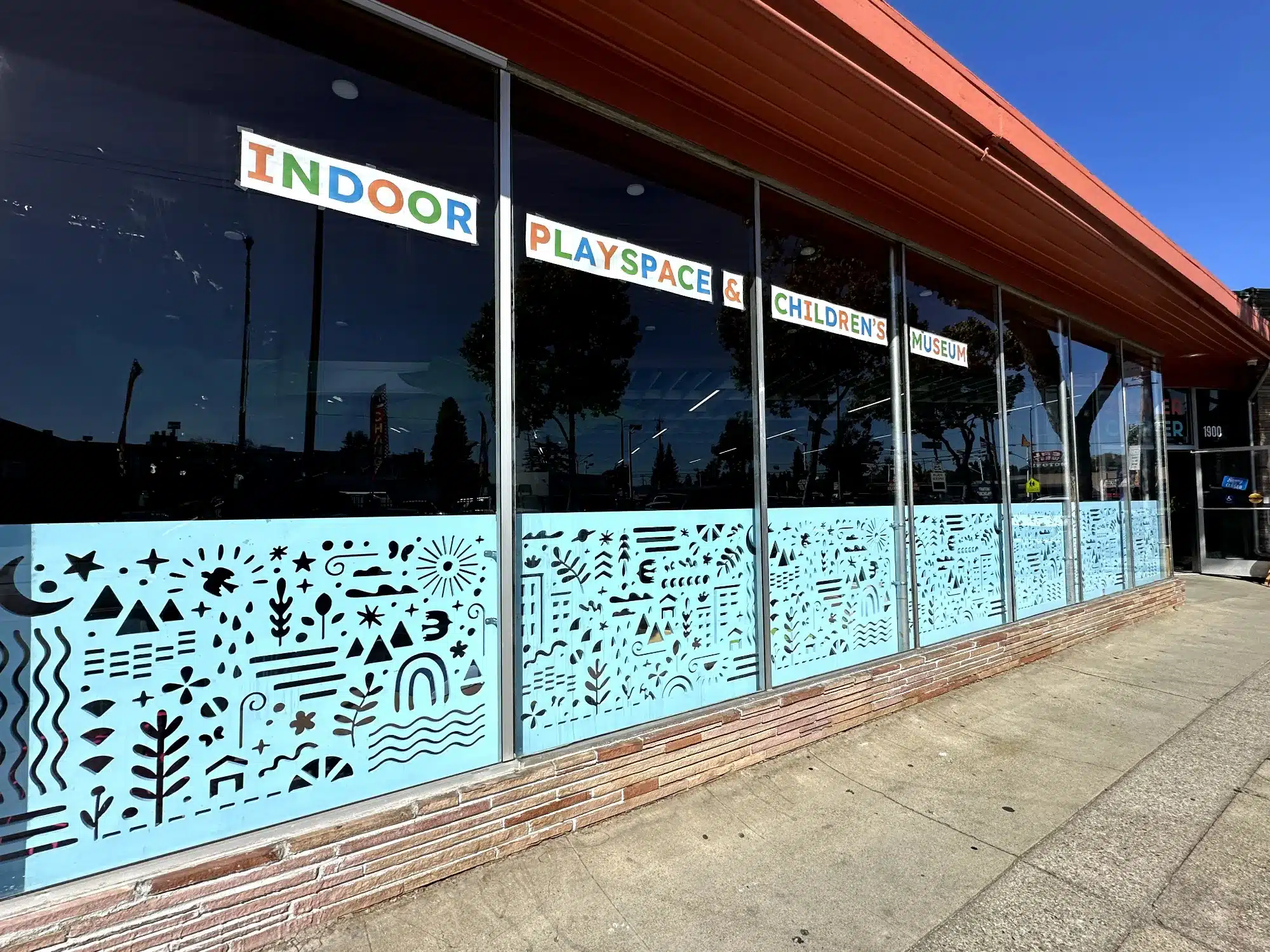 Light Blue Commercial Window Film Light blue storefront window film with black geometric patterns and doodles on commercial building in Oakland, CA