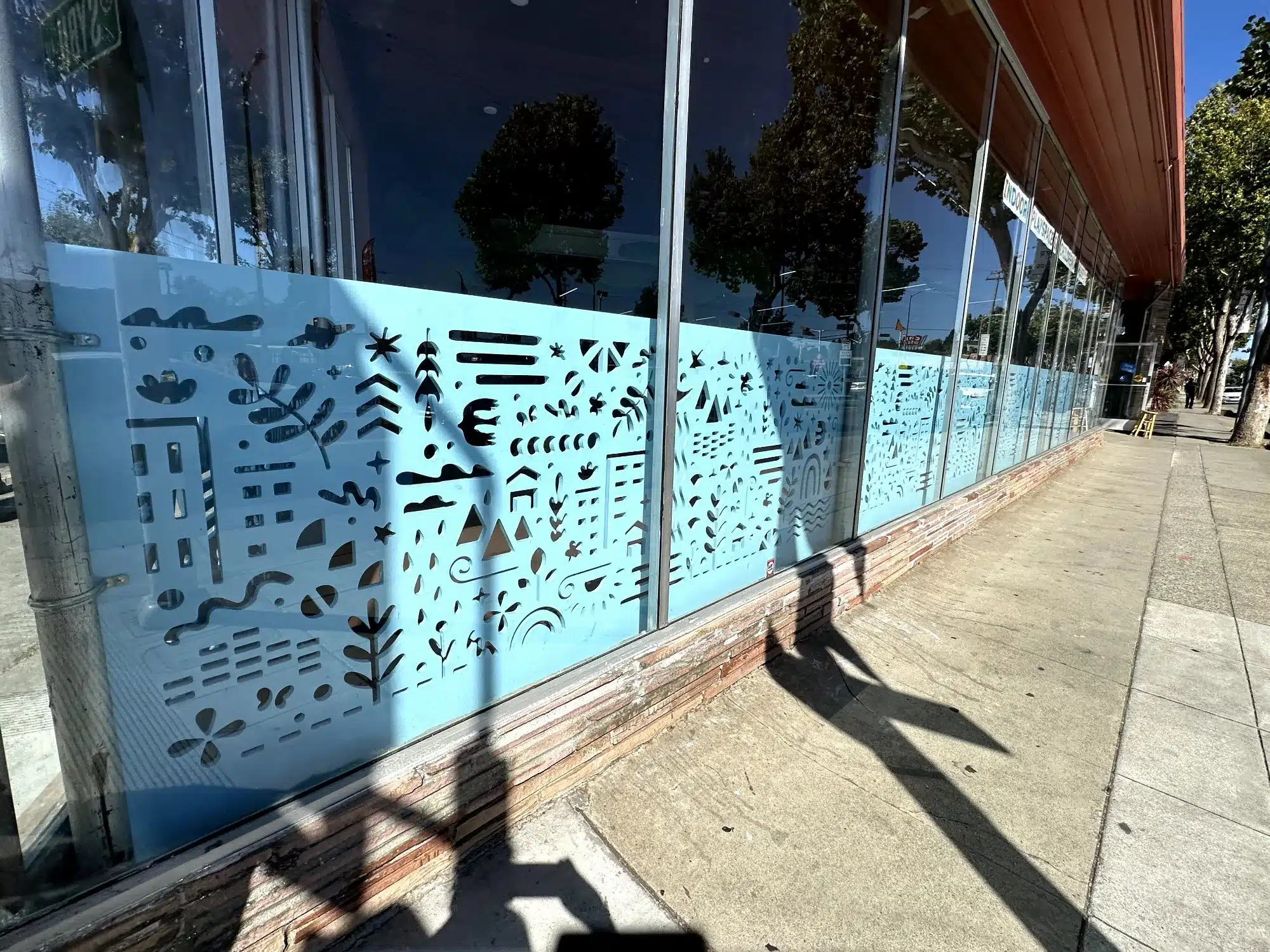 Light Blue Decorative Window Film Commercial Light blue decorative window film with geometric black patterns on commercial storefront glass in Oakland, CA