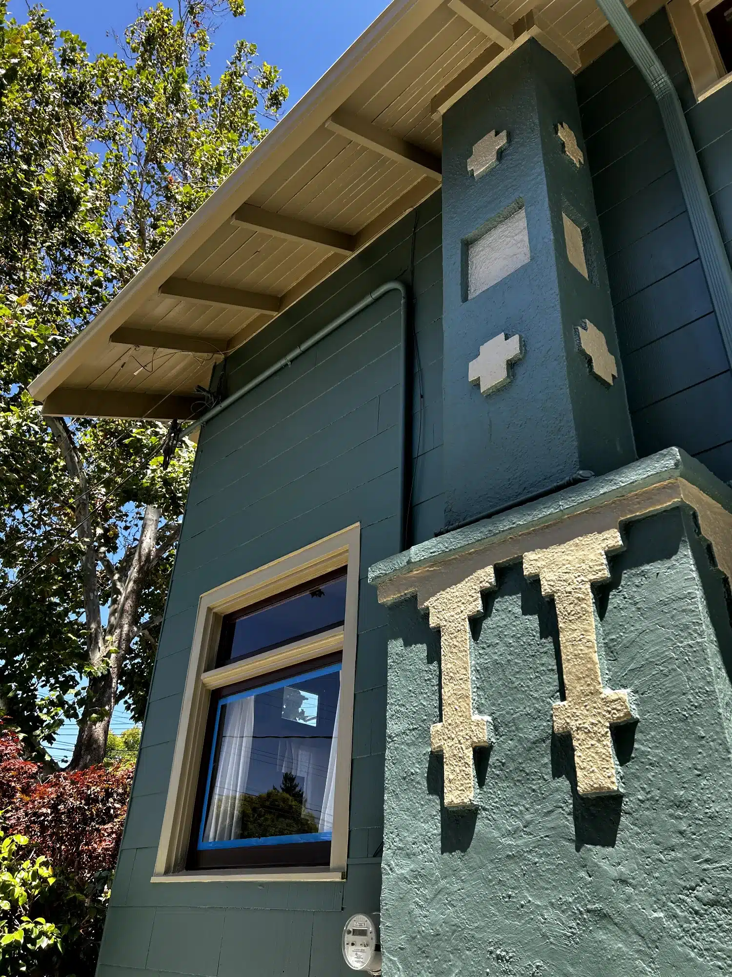 Dark Green Exterior Residential Addition Dark green-painted exterior residential addition with gold-trimmed window, decorative corbels, and white accent patches in