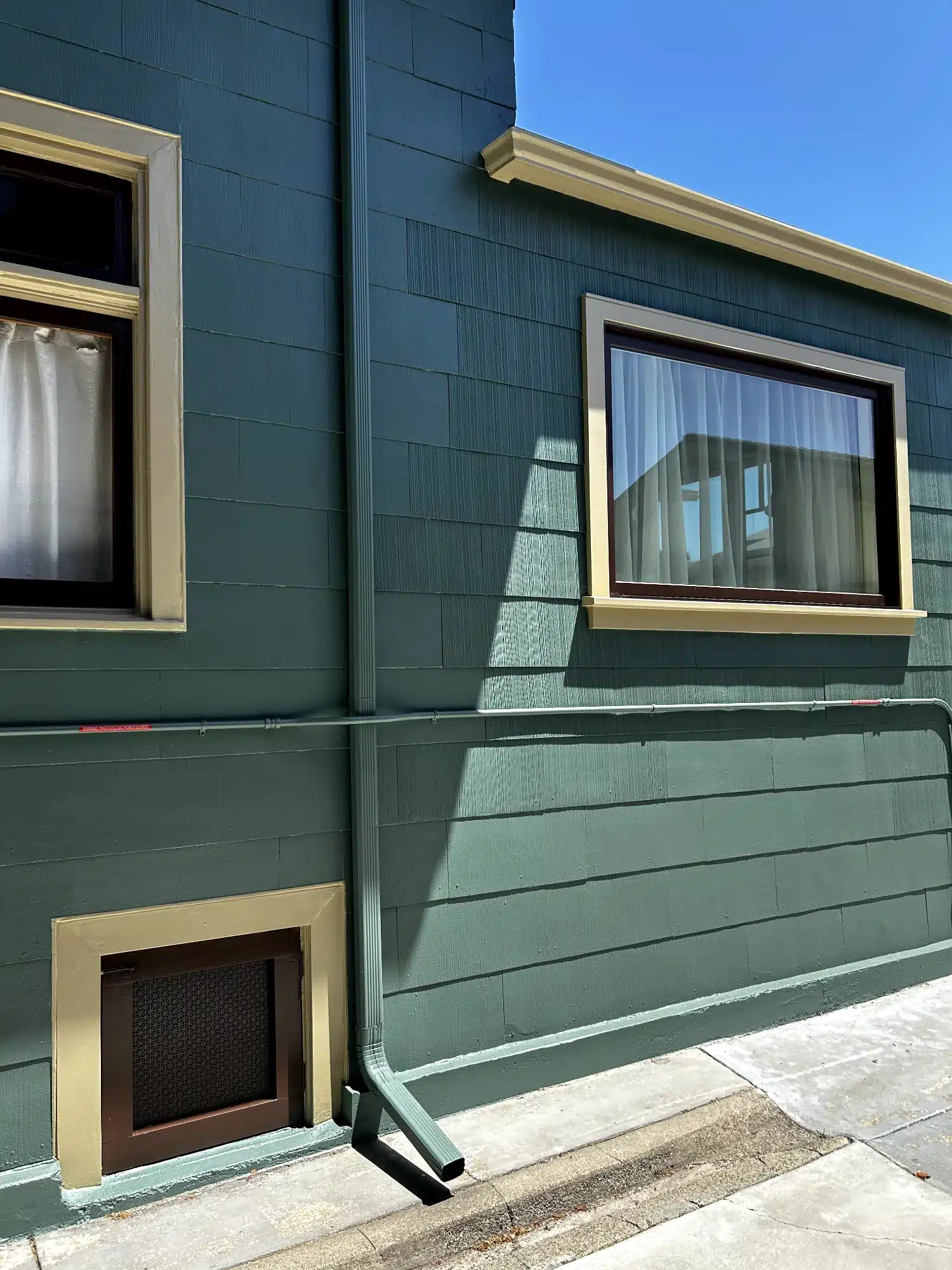 Dark Green Exterior Residential Siding Dark green-painted exterior residential wall with cream-trimmed windows, metal soffit, and horizontal siding in Oakland, CA