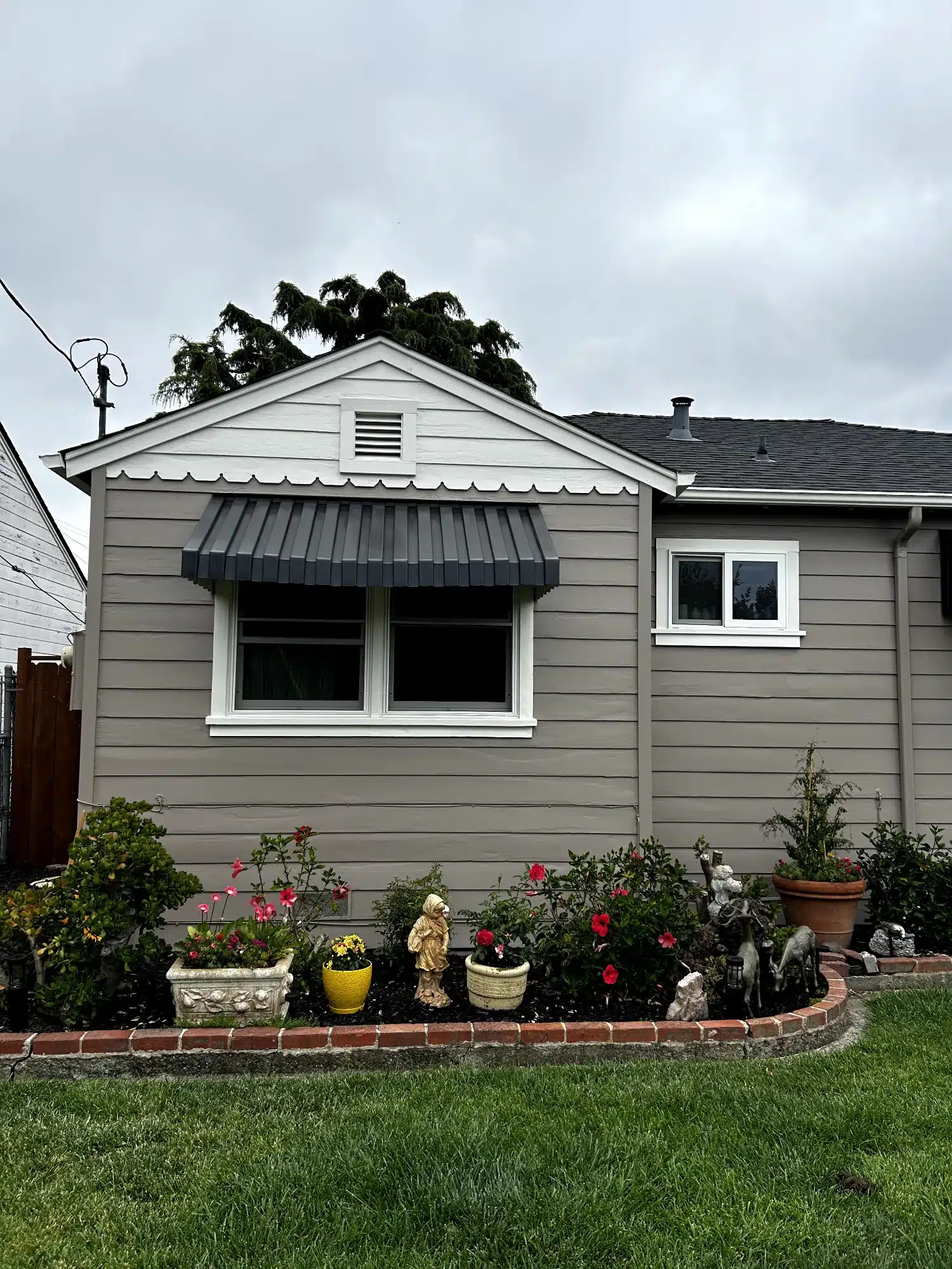 Gray Horizontal Siding Home Oakland Gray horizontal siding residential home with white-trimmed windows, black metal awning, and decorative front landscaping in