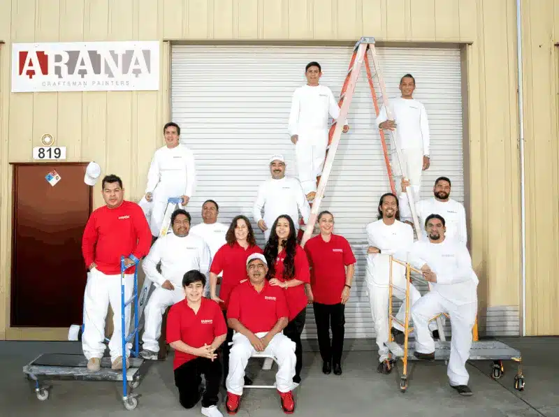 Arana Craftsman Painters Professional Team Ready for Service Arana Craftsman Painters team in uniforms, posing with ladders and scaffolding outside their building, ready for painting projects.